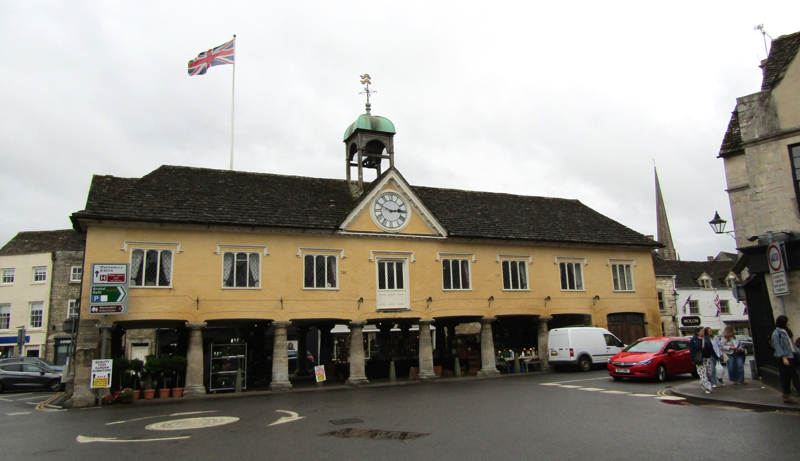 The 1655 Market House at Tetbury standing on stone pillars with a clock, bell turret and the church spire behind