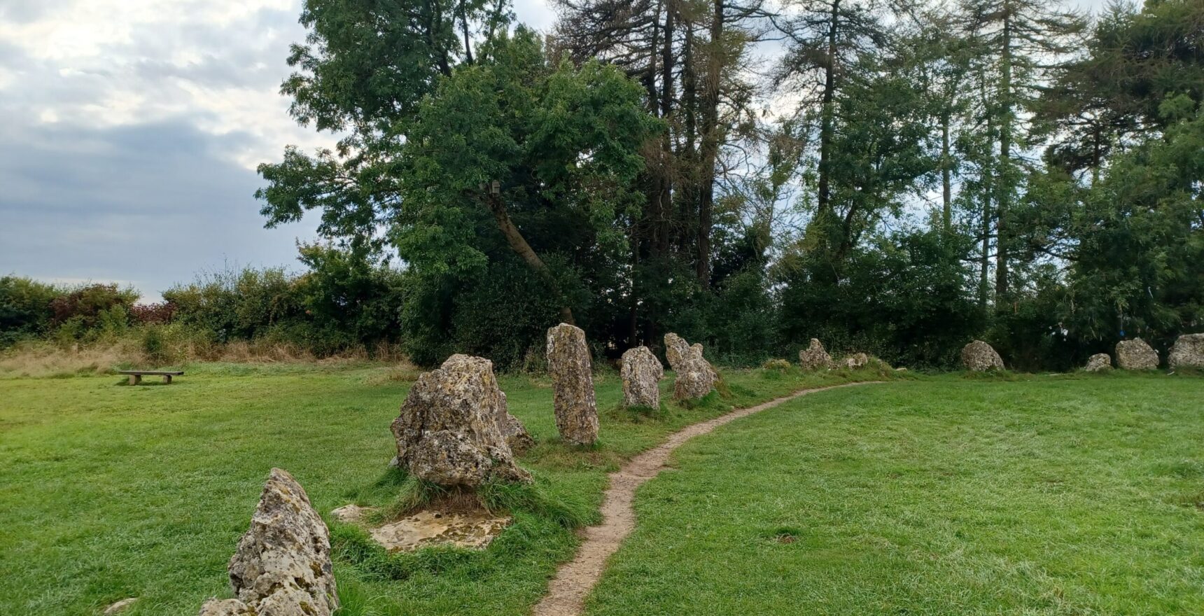 Weathered limestone uprights of the King's Men stone circle at the Rollright Stones, with a worn path between them under a broad sky