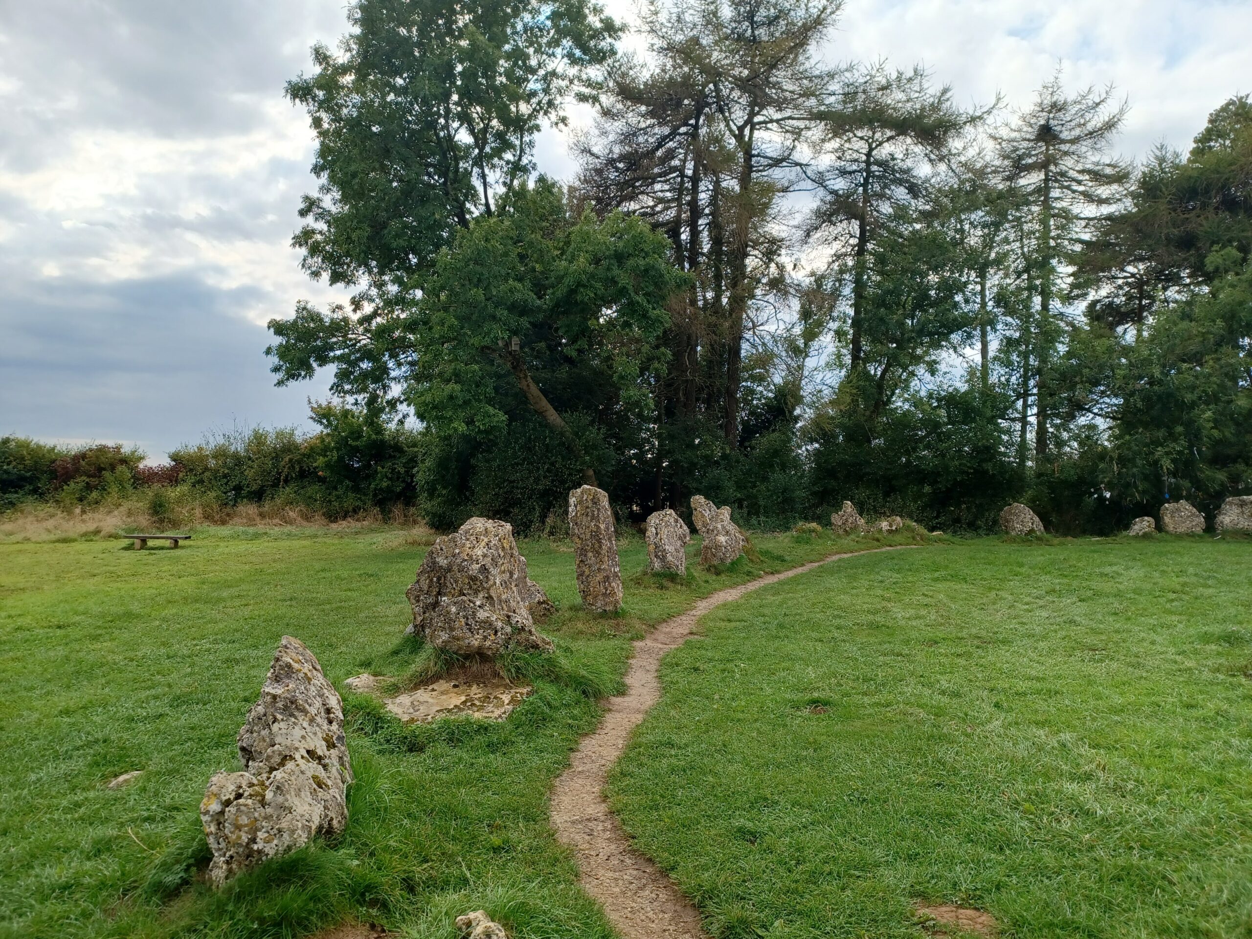 Weathered limestone uprights of the King's Men stone circle at the Rollright Stones, with a worn path between them under a broad sky